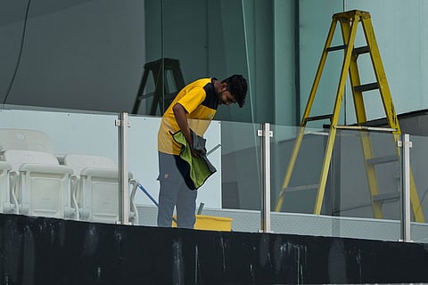 A worker cleans the glasses of an enclosure of the Gaddafi Stadium in preparations for upcoming Pakistan's premier domestic T20 the Pakistan Super League, which will take place in empty stadiums due to the recent spike in oil prices, in Lahore, Pakistan.