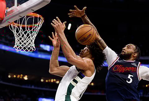 Milwaukee Bucks center Jericho Sims (00) and LA Clippers forward Derrick Jones Jr. (5) jump up for a rebound during the first half of an NBA basketball game in Inglewood, California.