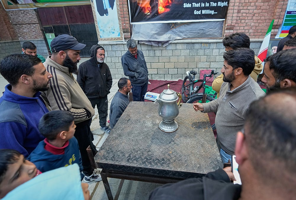 A volunteer auctions a donated copper vessel to raise cash for a relief drive for Iran in Budgam, Kashmir.