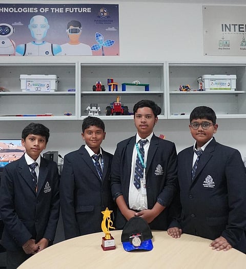 Four students in blazers with a school trophy