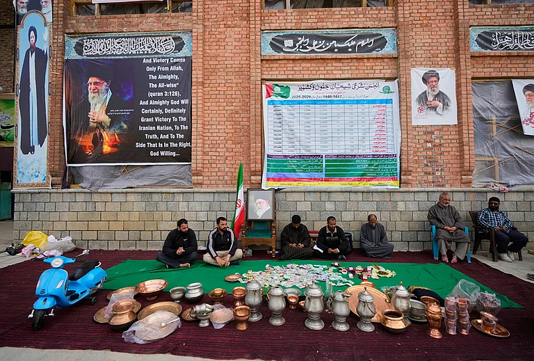 Volunteers wait at a collection point during a donation drive for Iran in Budgam, Kashmir. - | Photo: AP/Mukhtar Khan