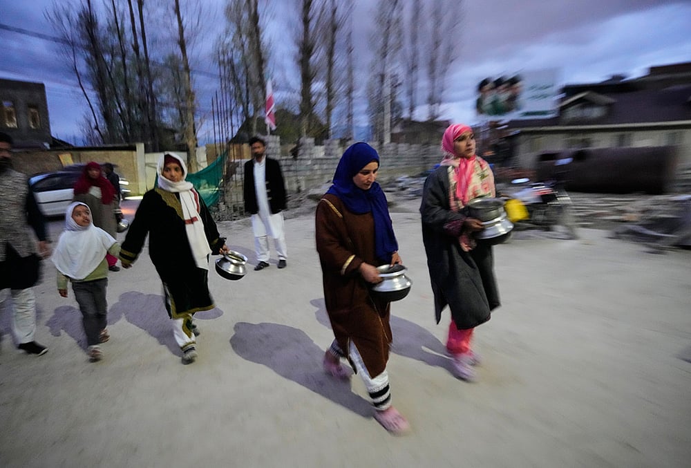 Shiite Muslim women arrive carrying kitchenware to donate at a relief drive for Iran in Budgam, Kashmir.