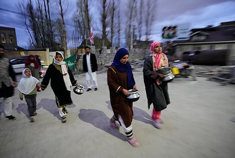 Shiite Muslim women arrive carrying kitchenware to donate at a relief drive for Iran in Budgam, Kashmir.