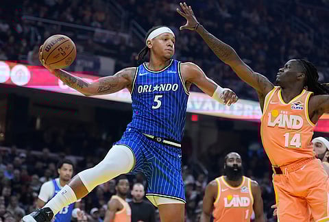 Orlando Magic forward Paolo Banchero (5) passes around Cleveland Cavaliers guard Keon Ellis (14) in the second half of an NBA basketball game in Cleveland.