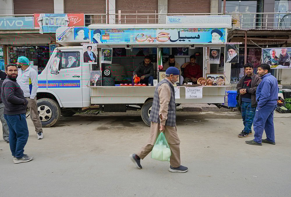 People walk past a van collecting donations for Iran in Budgam, Kashmir.
