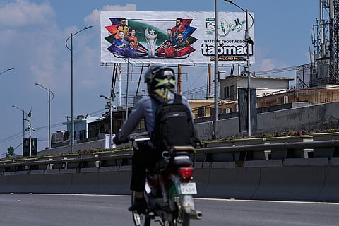 A motorcyclist drives past a billboard of Pakistan's premier domestic T20 the Pakistan Super League, which will take place in empty stadiums due to the recent spike in oil prices, in Rawalpindi, Pakistan.