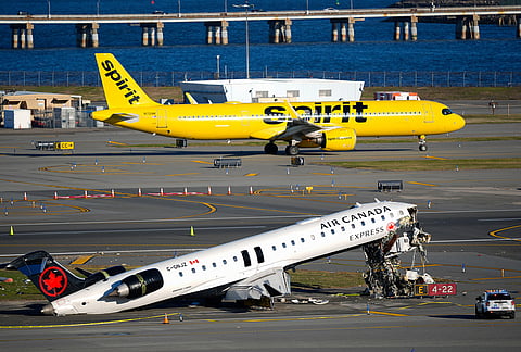A Spirit Airlines jet taxis past an Air Canada Express jet sitting on the side of a runway, where it had collided with a Port Authority fire truck Sunday night at LaGuardia Airport in New York. 