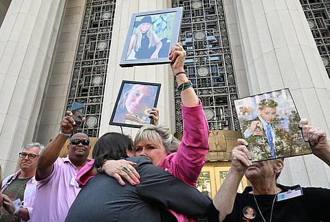 Lori Schott, center, is embraced as she holds up a photo of her daughter Annalee Schott, after the verdict in a landmark trial over whether social media platforms deliberately addict and harm children at Los Angeles Superior Court in Los Angeles. 