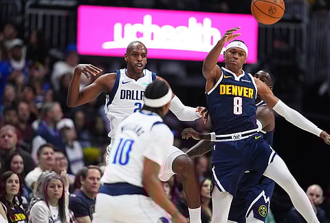 Denver Nuggets guard Peyton Watson, back right, passes the ball as Dallas Mavericks forward Khris Middleton, back left, and guard Brandon Williams defend in the second half of an NBA basketball game in Denver.