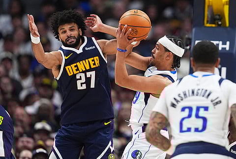 Dallas Mavericks guard Ryan Nembhard, right, passes the ball a Denver Nuggets guard Jamal Murray defends in the second half of an NBA basketball game in Denver. 