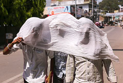 People cover themselves while walking on a hot sunny day, in Prayagraj, Uttar Pradesh.