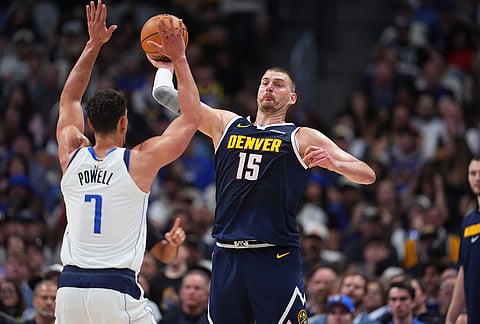 Denver Nuggets center Nikola Jokić, back, fires the ball in an unsuccessful attempt to hit a basket over Dallas Mavericks forward Dwight Powell as time runs out in the third quarter of an NBA basketball game in Denver.