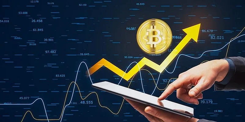 Hand using tablet with Bitcoin icon and rising crypto market chart