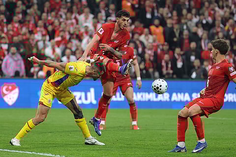 Turkey's Samet Akaydin, center, vies for the ball with Romania's Andrei Burca during the 2026 World Cup playoff semifinal soccer match between Turkey and Romania, in Istanbul, Turkey.
