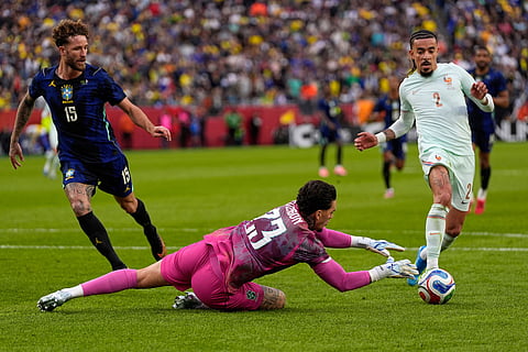 Brazilian goalkeeper Ederson saves at the feet of Malo Gusto of France during the international friendly soccer match between Brazil and France in Foxborough, Mass.