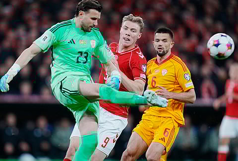 Denmark's Rasmus Hojlund, center, between North Macedonia's goalkeeper Stole Dimitrievski and Visar Musliu during the World Cup playoff semifinal soccer match between Denmark and North Macedonia in Copenhagen.