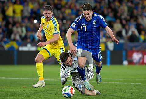 Sweden's Viktor Gyokeres, top, and Ukraine's goalkeeper Anatoliy Trubin challenge for the ball during a World Cup playoff semifinal soccer match between Ukraine and Sweden in Valencia, Spain.