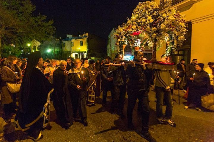 People carrying a floral religious platform in a nighttime candlelit procession.