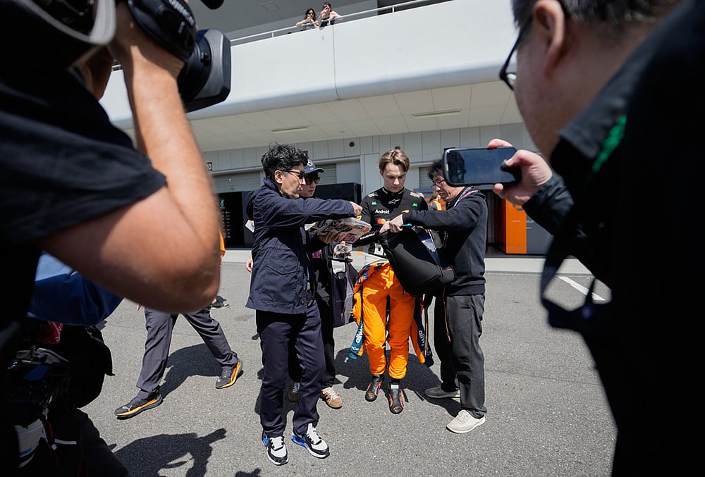 McLaren driver Oscar Piastri of Australia gives autograph to fans after the first practice session of the Japanese Formula One Grand Prix in Suzuka, Japan. - | Photo: AP/Eugene Hoshiko