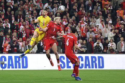 Romania's Radu Dragusin, top left, vies for a high ball with Turkey's Baris Alper Yilmaz during the 2026 World Cup playoff semifinal soccer match between Turkey and Romania, in Istanbul, Turkey.