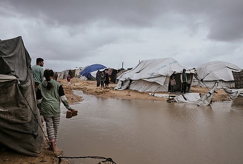 Palestinians walk through a flooded area in a temporary tent camp after heavy rainfall in Gaza City.