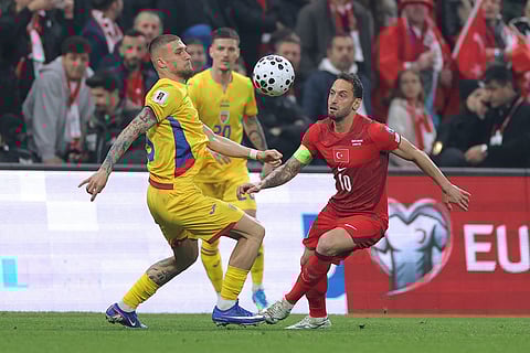 Romania's Daniel Birligea, left, battles for the ball with Turkey's Hakan Calhanoglu during the 2026 World Cup playoff semifinal soccer match between Turkey and Romania, in Istanbul, Turkey.
