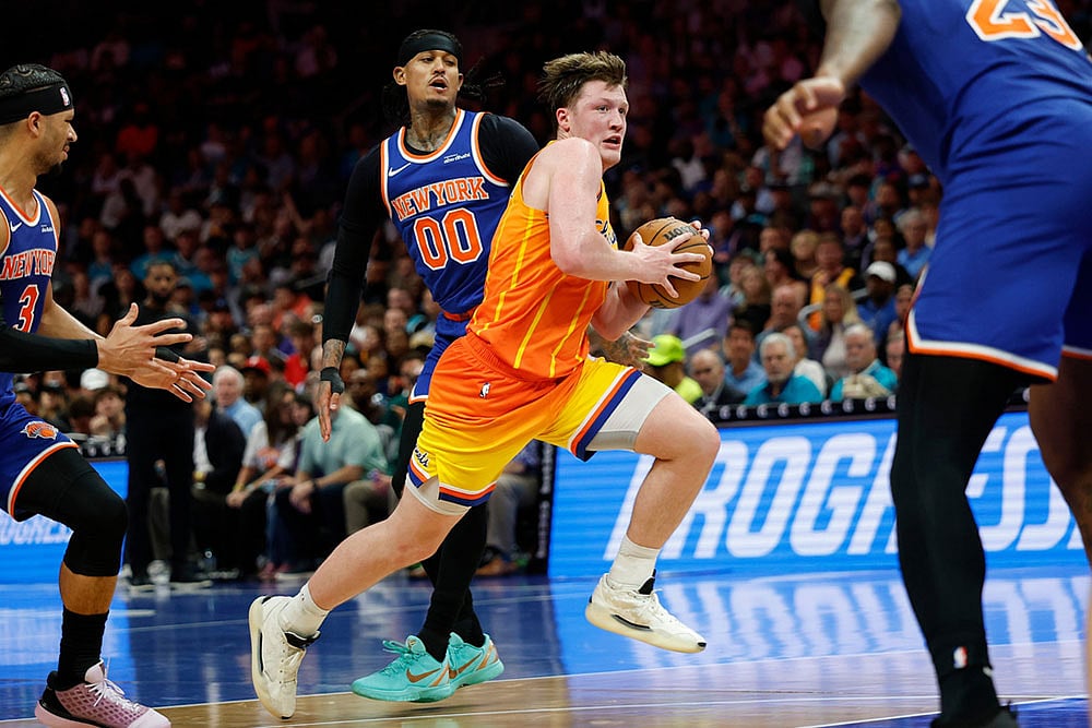 Charlotte Hornets guard Kon Knueppel, center front, drives to the basket past New York Knicks guards Josh Hart, left, and Jordan Clarkson (00) during the second half of an NBA basketball game in Charlotte, N.C. - | Photo: AP/Nell Redmond