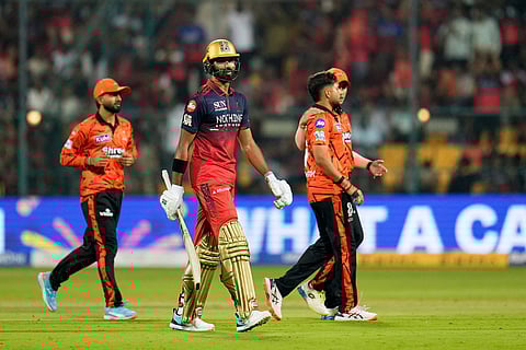 Royal Challengers Bengaluru's Devdutt Padikkal, center, leaves the ground after losing his wicket during the Indian Premier League cricket match between Royal Challengers Bengaluru and Sunrisers Hyderabad in Bengaluru, India.