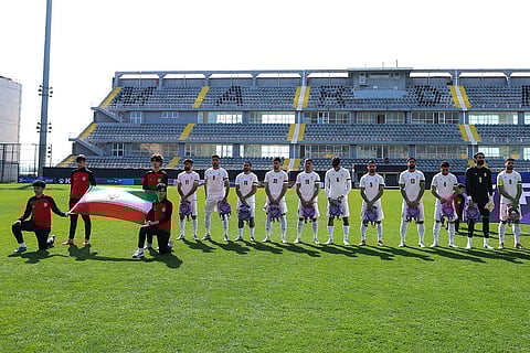 Iran players pose with kids backpacks as they listen the National Anthem before the Iran vs Nigeria friendly soccer match in Antalya, Turkey