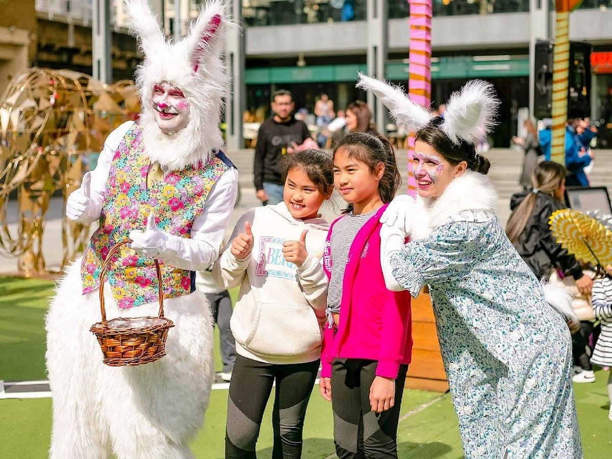 Children posing with Easter bunny performers at an outdoor event