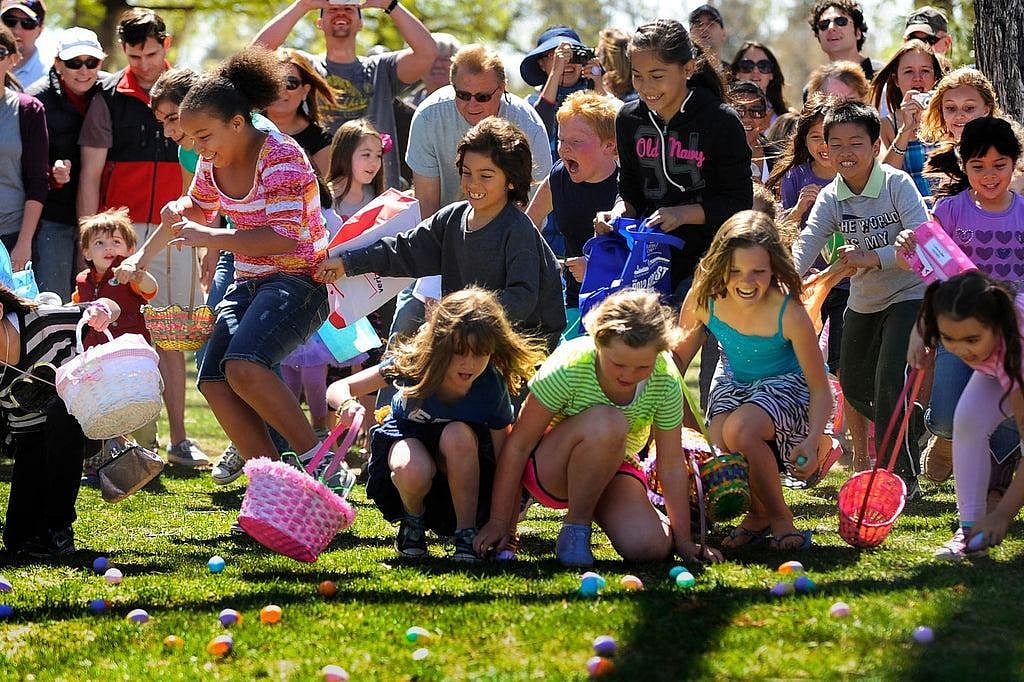 Kids excitedly collecting eggs during an outdoor Easter egg hunt