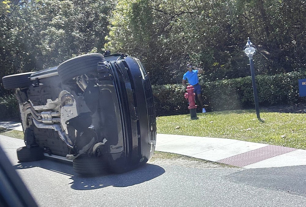 Golfer Tiger Woods stands by his overturned vehicle in Jupiter Island, Florida.. - | Photo: AP/Jason Oteri