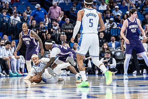 Orlando Magic guard Jalen Suggs (4) fights for the ball against Sacramento Kings guard/forward Daeqwon Plowden (29) during the first half of an NBA basketball game in Orlando, Fla.