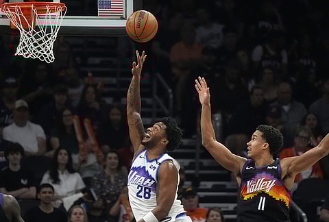 Utah Jazz forward Brice Sensabaugh (28) gets off a shot against Phoenix Suns forward Oso Ighodaro (11) during the first half of an NBA basketball game, in Phoenix.