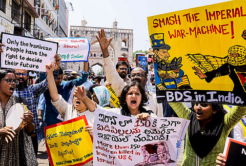 Activists hold placards during a protest rally against the ongoing West Asia conflict, near Charminar in Hyderabad, Telangana.