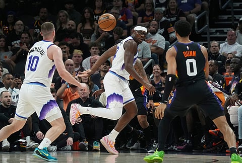Utah Jazz center Oscar Tshiebwe, center, saves the ball to Jazz guard Svi Mykhailiuk (10) as Phoenix Suns forward Ryan Dunn (0) looks on during the second half of an NBA basketball game in Phoenix.