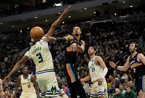 San Antonio Spurs' Victor Wembanyama passes the ball around Milwaukee Bucks' Myles Turner during the second half of an NBA basketball game in Milwaukee.