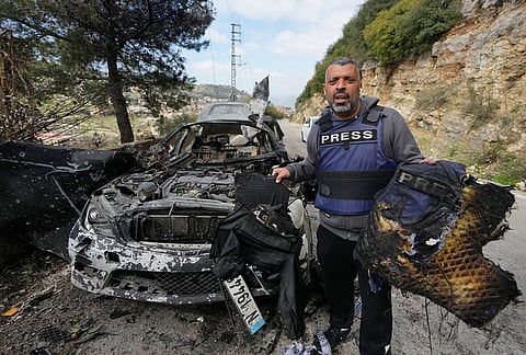 A journalist carries burned safety gear, following an Israeli airstrike on a car that killed Hezbollah's al-Manar TV correspondent Ali Shoeib, Beirut's based Al-Mayadeen TV reporter Fatima Ftouni and her brother, video journalist Mohammed Ftouni, in the town of Jezzine, south Lebanon.