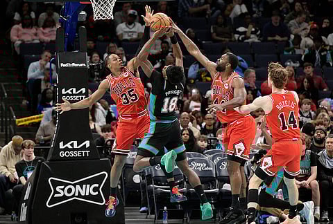 Memphis Grizzlies forward Olivier-Maxence Prosper (18) jumps to shoot between Chicago Bulls forwards Isaac Okoro (35) and Patrick Williams (44) in the first half of an NBA basketball game in Memphis, Tennessee.