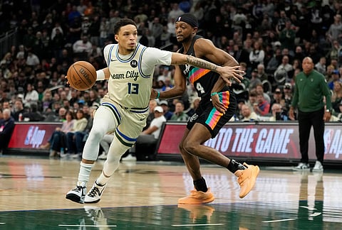 Milwaukee Bucks' Ryan Rollins (13) drives to the basket against San Antonio Spurs' De'Aaron Fox during the first half of an NBA basketball game in Milwaukee.