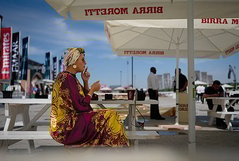 A racegoer smokes a cigarette at Meydan Racecourse ahead of the Dubai World Cup, United Arab Emirates.