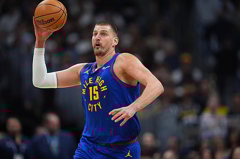 Denver Nuggets center Nikola Jokić thorws the ball in an attempt to make a basket as time runs out in the first quarter of an NBA basketball game against the Golden State Warriors in Denver.