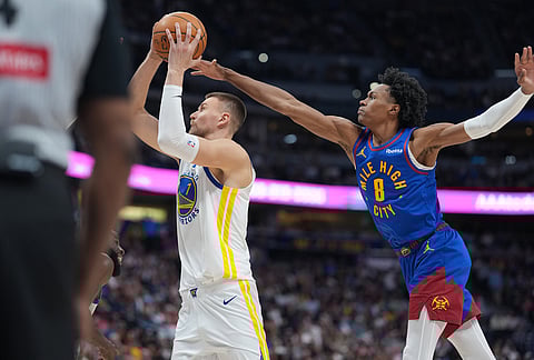 Golden State Warriors forward Kristaps Porziņģis, left, goes up for a basket as Denver Nuggets guard Peyton Watson defends in the second half of an NBA basketball game in Denver.