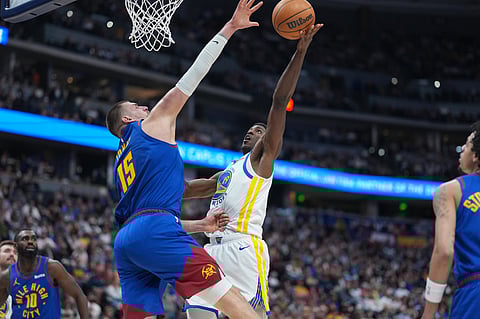 Golden State Warriors guard Nate Williams, right, goes up for a basket as Denver Nuggets center Nikola Jokić defends in the second half of an NBA basketball game in Denver.