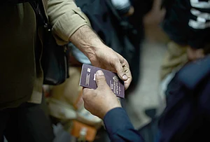 | Photo: AP/Leo Correa : An Iraqi border police officer checks the passport of a man arriving from Iran as he crosses the Shalamcheh border crossing between Iran and Iraq, near Basra, Iraq.