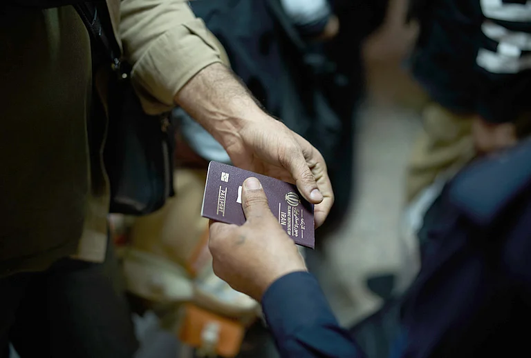An Iraqi border police officer checks the passport of a man arriving from Iran as he crosses the Shalamcheh border crossing between Iran and Iraq, near Basra, Iraq. - | Photo: AP/Leo Correa