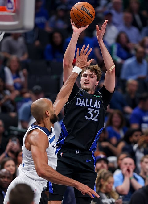 Dallas Mavericks forward Cooper Flagg (32) scores over Minnesota Timberwolves center Rudy Gobert (27) in the first half of an NBA basketball game in Dallas.