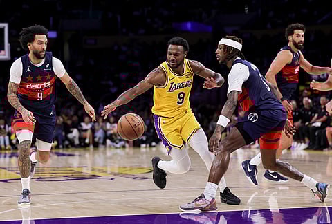 Los Angeles Lakers guard Bronny James, center, drives against Washington Wizards guard Jamir Watkins, right, and forward Justin Champagnie during the second half of an NBA basketball game in Los Angeles.