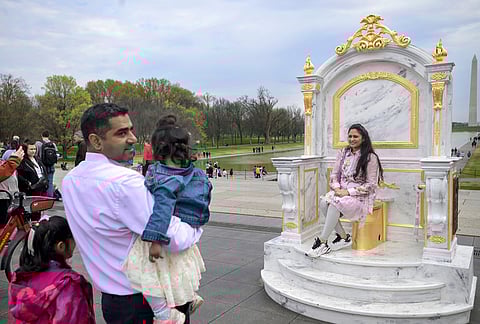 Following a weekend marked by No Kings protests, people take photos of a piece of protest art titled "A throne fit for a king" near the Lincoln Memorial in Washington. 