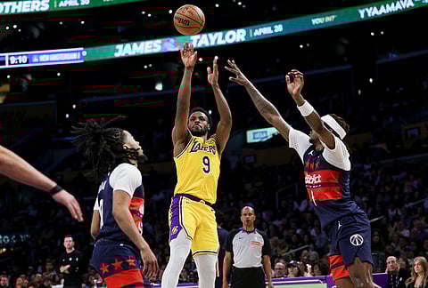 Los Angeles Lakers guard Bronny James, center, shoots against Washington Wizards guard Sharife Cooper, left, and guard Jamir Watkins during the second half of an NBA basketball game in Los Angeles.